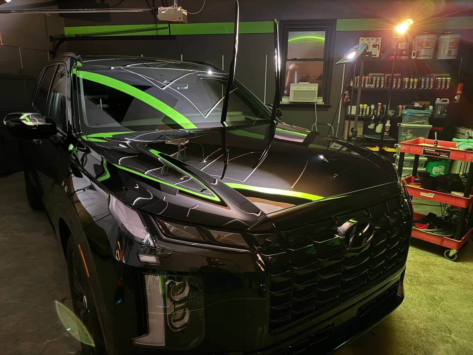 Black Hyundai Palisade hood reflecting the shop's green stripe